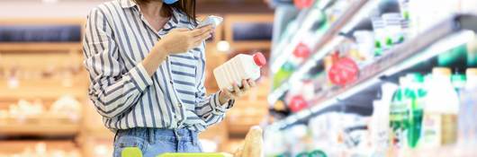 Person in supermarket checking a label on a food product