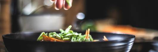 Sprinkling shredded vegetables in a pan for Korean pancakes.