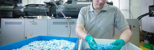 Worker inspecting recycled plastic in plastics factory