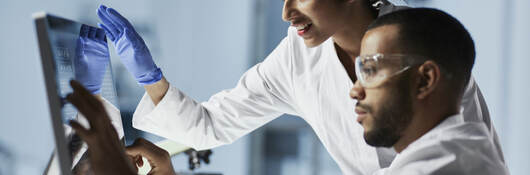 Scientists in laboratory working with computer and microscope