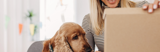 Woman sitting next to her dog while opening a package