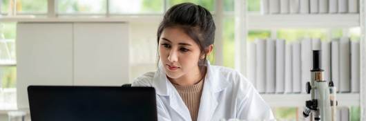 Asian woman scientist student checking results on laptop in laboratory