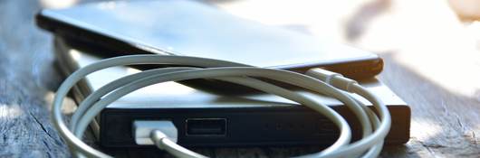 Close-up of mobile phone connected to portable charger on table