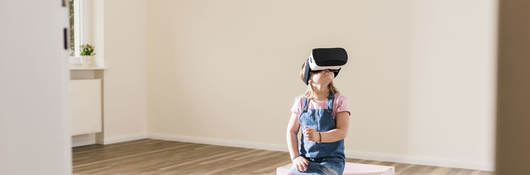 Little girl wearing a VR headset with a teddy bear