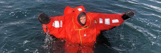 A person wearing an immersion suit and floating in water