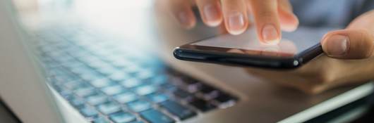 Close-up of a businesswoman using a phone and laptop.