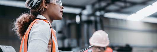 Female engineer wearing a helmet while standing in a factory 