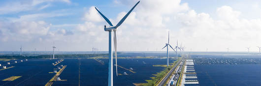 Solar power stations with wind turbines in distance