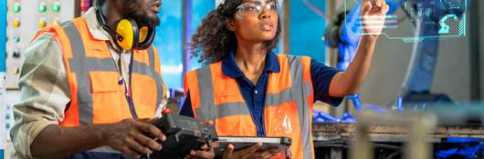 Engineer using tablet to check the robot system while her teamwork checks the security of the robot.