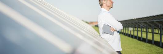 Man standing in front of a row of solar panels. 