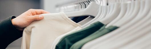 Cropped hand of man holding shirt in shop.