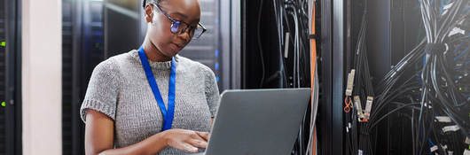 Person working on laptop in server room 