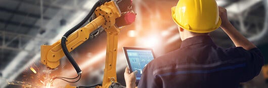 Worker overseeing automated machines in warehouse 