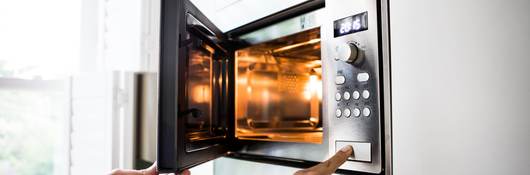 A man using a microwave oven. His finger on the opening button.