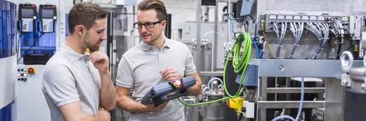 Two men with a control system on factory shop floor.