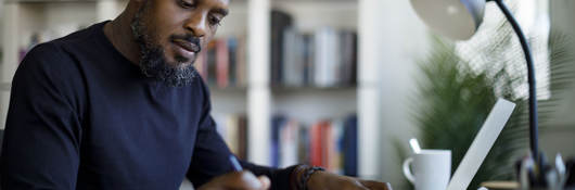 Person writing notes while sitting at a desk