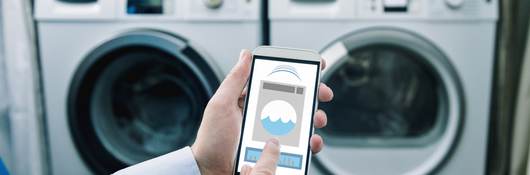 Consumer using mobile phone app to control washing machine.