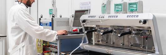 Laboratory technician conducting test on espresso machine.