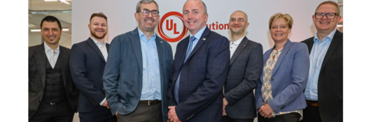 Leadership pictured in front of white wall with UL Solutions logo