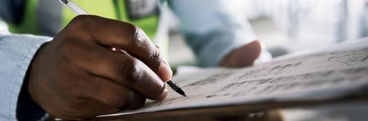 Shot of an unrecognisable builder filling out paperwork at a construction site