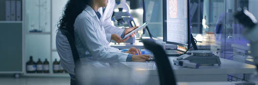 Two scientists in the lab viewing data on a laptop