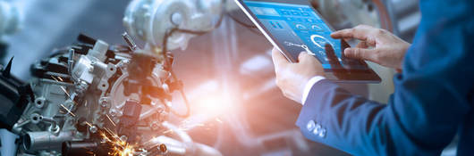 Person using tablet to control robotic arm in a factory