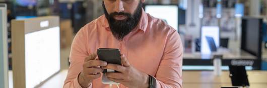 Young man testing out a mobile phone.