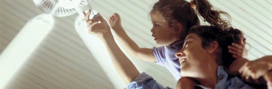 Mother and daughter turning on a ceiling fan.