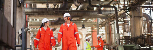 Workers wearing PPE and walking at oil refinery