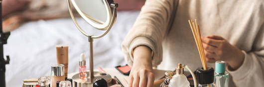 reaching out to pick up a lipstick from a table full of beauty products