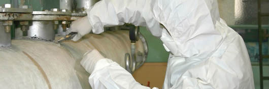 A worker wearing PPE and working with asbestos