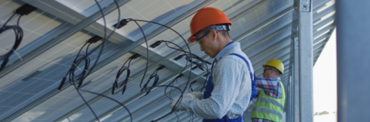 Two solar panel installers twisting wire 