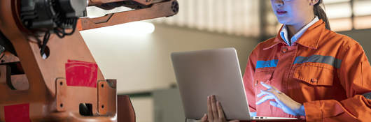 Person in factory working on a laptop