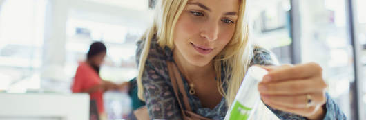 Customer examining skincare product in drugstore