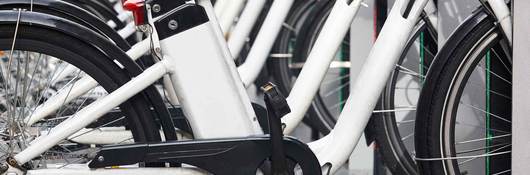 Row of white electric bikes lined up on a bike rack