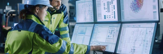 Project engineer talks to female operator who controls facility production line.