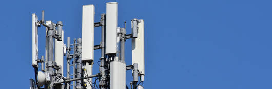 Antennas on a roof with blue sky behind it. 