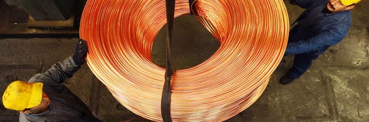Workers moving roll of copper wire.