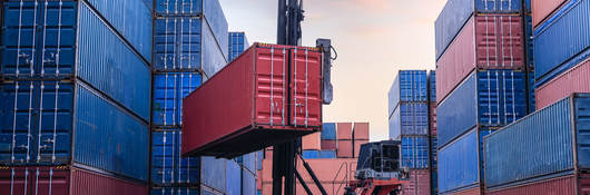 Forklift truck handling cargo shipping container box in logistic shipping yard with cargo container stack