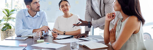 Four people attending a meeting in an office with lots of bright windows