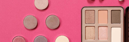 Palette of eye shadow in gold tones on a pink background