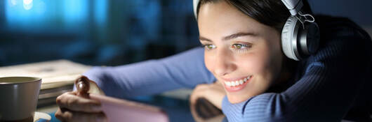 Woman wearing headphones and watching media on mobile phone
