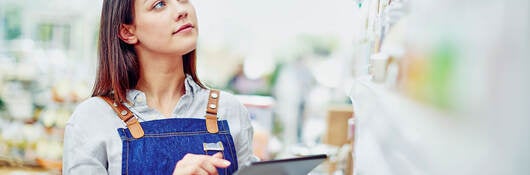 A young person holding a tablet and doing inventory in a store