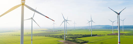 Sun shining over wind turbines on a wind farm