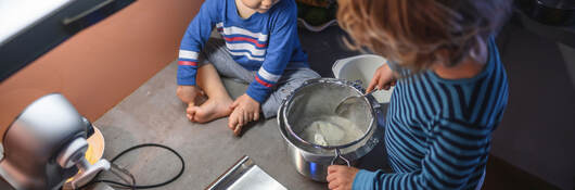 Two children using a food scale to measure out ingredients 