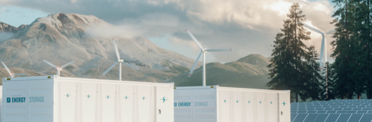 Energy storage, wind turbines and solar panels with mountains in the background