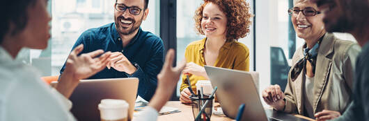 Business people talking in a meeting and using laptops and other devices