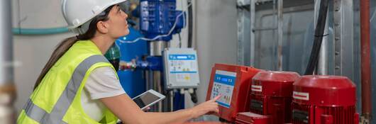 Female engineer doing quality control of water pumping engines in basement.