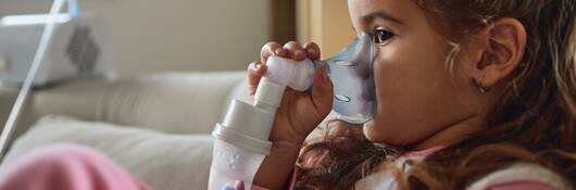 Young child using nebulizer during inhaling therapy