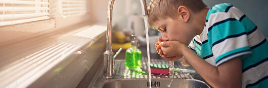 young person drinking tap water from the faucet